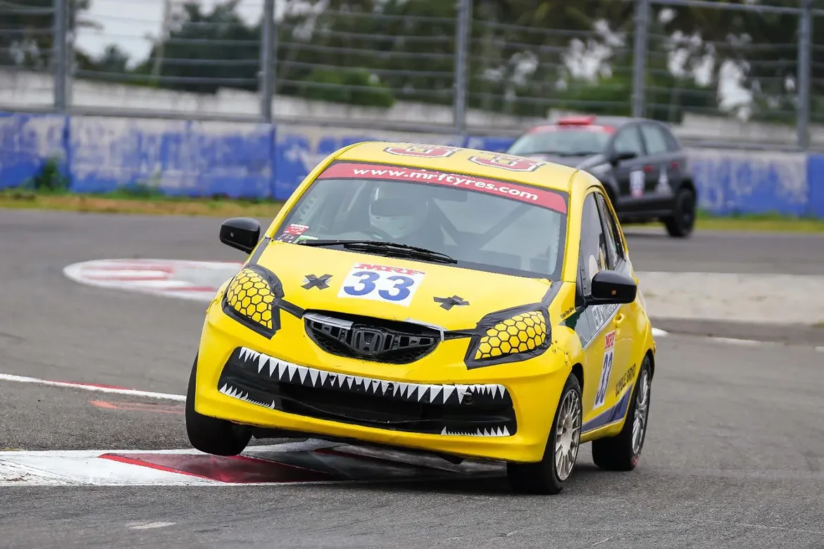 Yellow #33 Honda Brio race car cornering on track